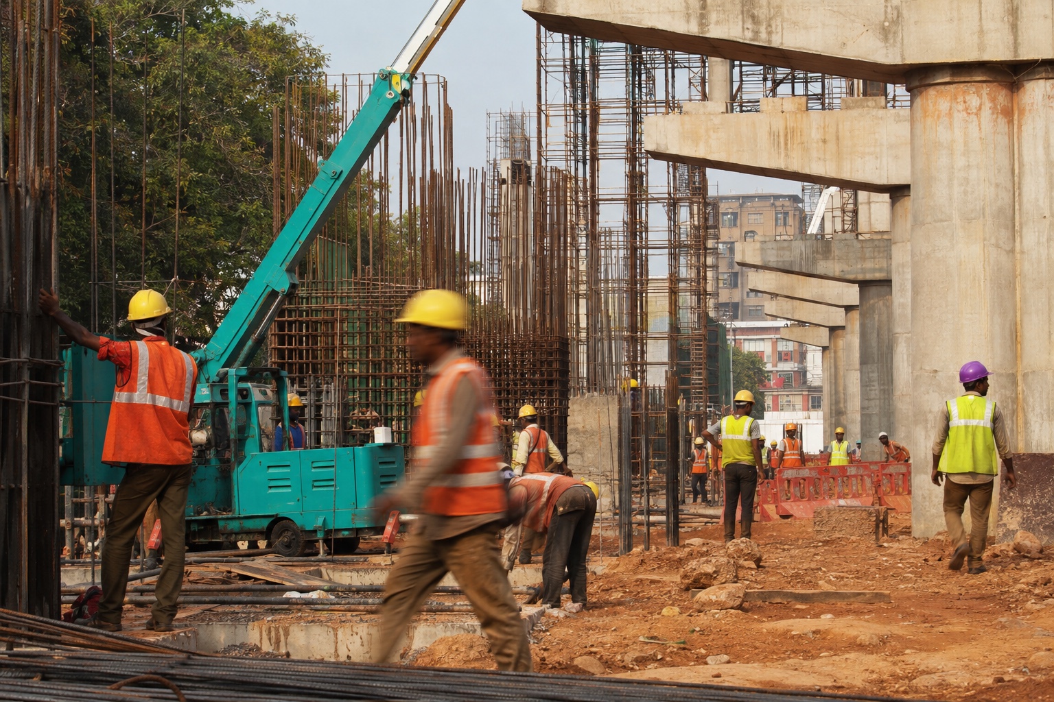 Indian construction crew working among concrete columns, rebar and dusty scaffolding